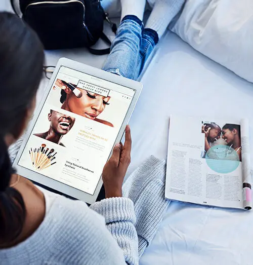 mulher sentada com um tablet na mão e um revista ao seu lado